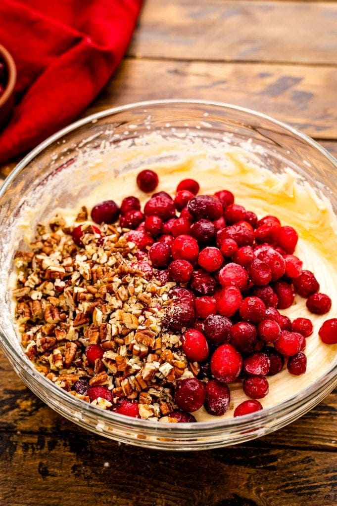 Batter in bowl with chopped pecans and cranberries on top before stirring.