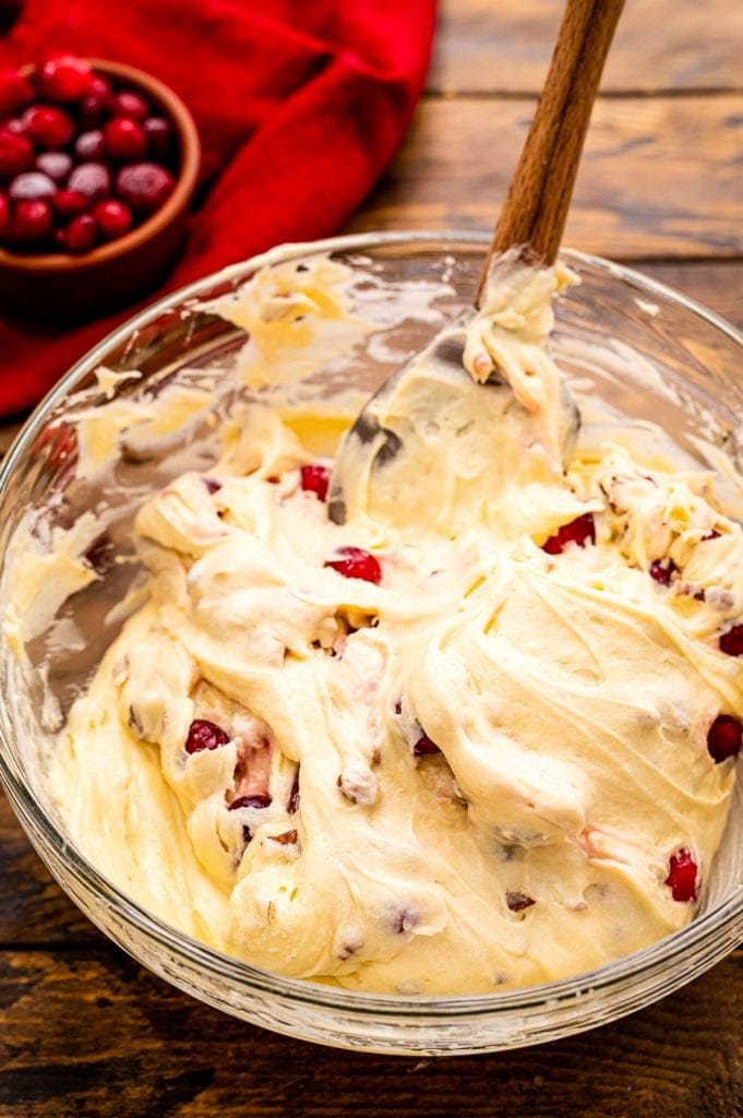 Bowl of batter for cranberry muffins with spoon in it.