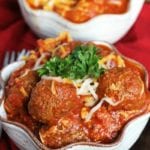 Two cream bowls of crock pot cheesy meatball tortellini on a red kitchen napkin