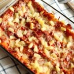 Hawaiian lasagna in a clear glass casserole pan sitting on a kitchen towel