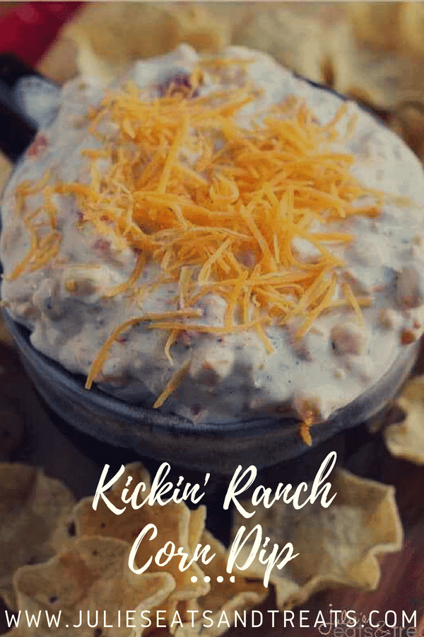 Kickin ranch corn dip in a bowl topped with shredded cheese and surrounded by tortilla chips