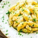 Cheesy garlic butter shell noodles in a white bowl topped with parsley
