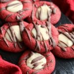 Red velvet fudge thumbprint cookies on a slate tray sitting on a red kitchen towel