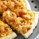 Shrimp mac 'n cheese pizza sliced on a metal pizza pan