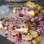 Berry cheesecake crumble bars stacked on wax paper