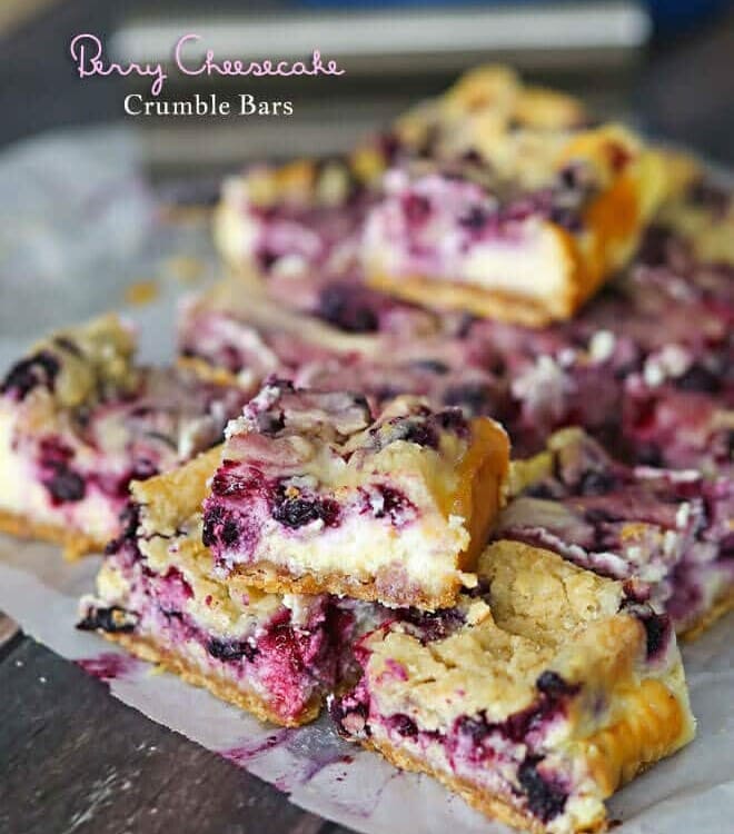 Berry cheesecake crumble bars stacked on wax paper