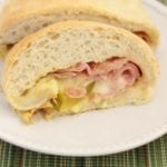 Two slices of stuffed ham and cheese bread on a white plate sitting on a green place mat