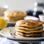 Stack of five blueberry pancakes with syrup on a plate with a fork
