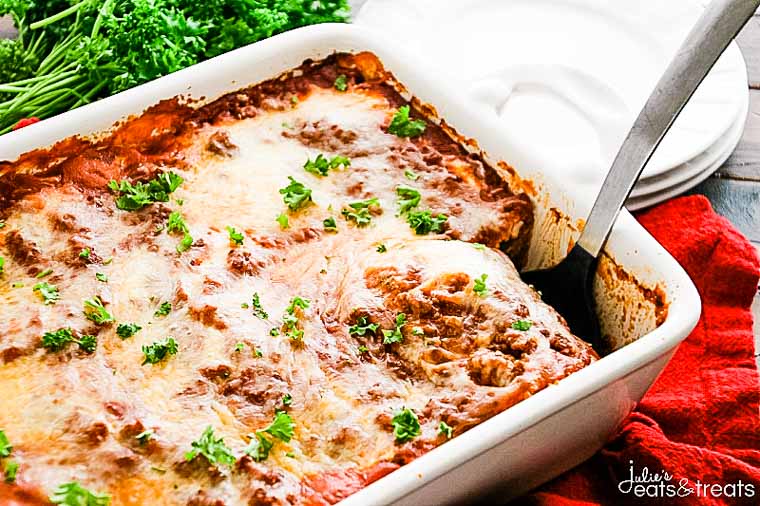 White baking dish with lasagna in it and a spatula scooping a piece out