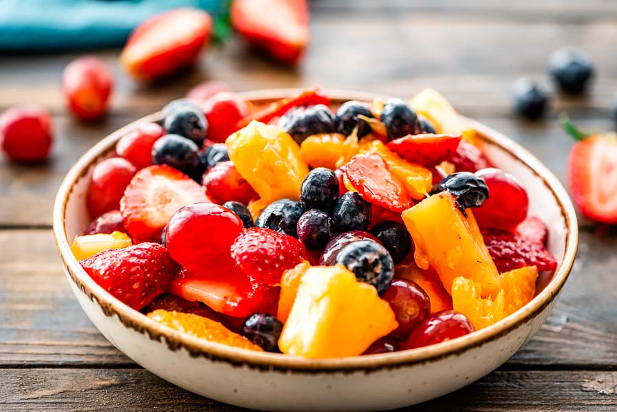 glazed fruit salad in serving bowl with blueberries, strawberries, grapes, pineapples