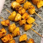 A row of barbecue potato kebabs on a stone tray