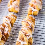 Baking rack with cinnamon twists and a powdered sugar icing on them on white background