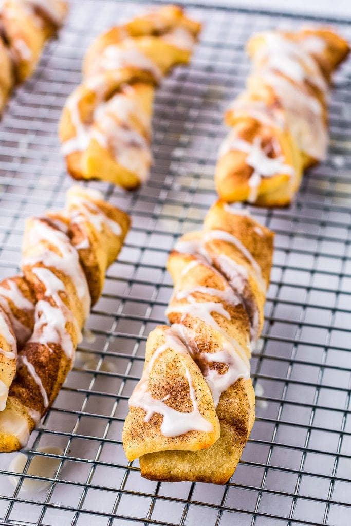 Baking rack with cinnamon twists and a powdered sugar icing on them on white background