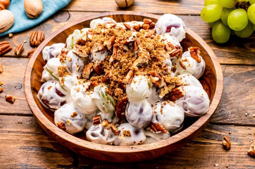 Bowl bowl with prepare grape salad in it with brown sugar and chopped pecans sprinkled on top.