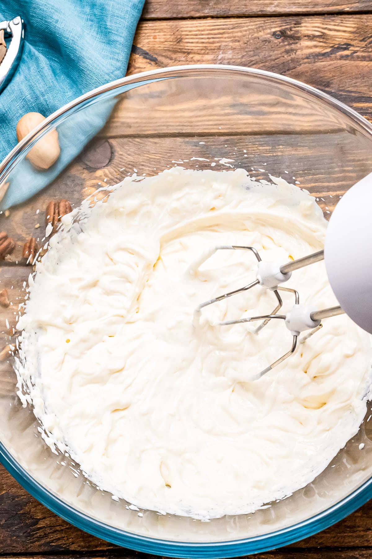 Hand mixer combining cream cheese and sour cream for dressing to make grape salad