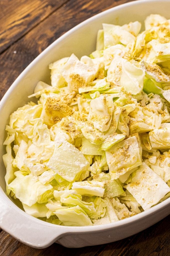 Cabbage, ground mustard in white oval baking dish before baking.