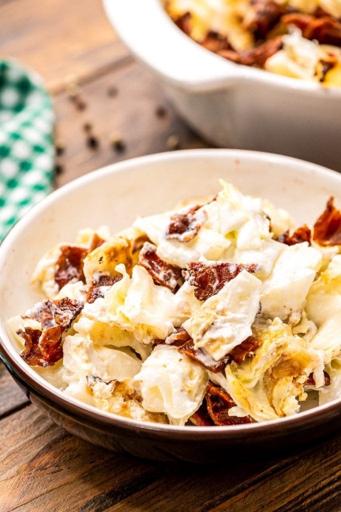 Bowl of mixed up cooked cabbage casserole with chopped bacon.