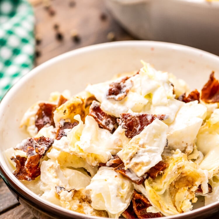 Bowl of mixed up cooked cabbage casserole with chopped bacon.