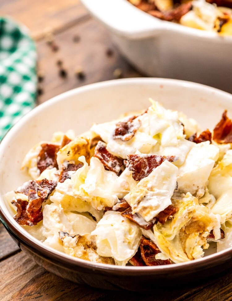 Bowl of mixed up cooked cabbage casserole with chopped bacon.