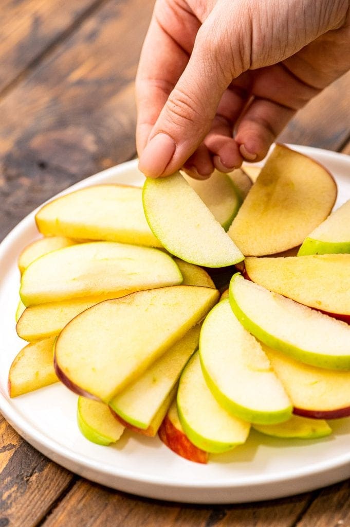 Hand placing sliced apples in a fan shape