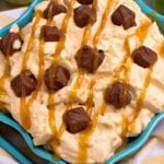 Blue square bowl of caramel apple snickers salad topped with caramel sauce