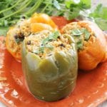 Three crock pot quinoa chicken stuffed peppers on an orange plate