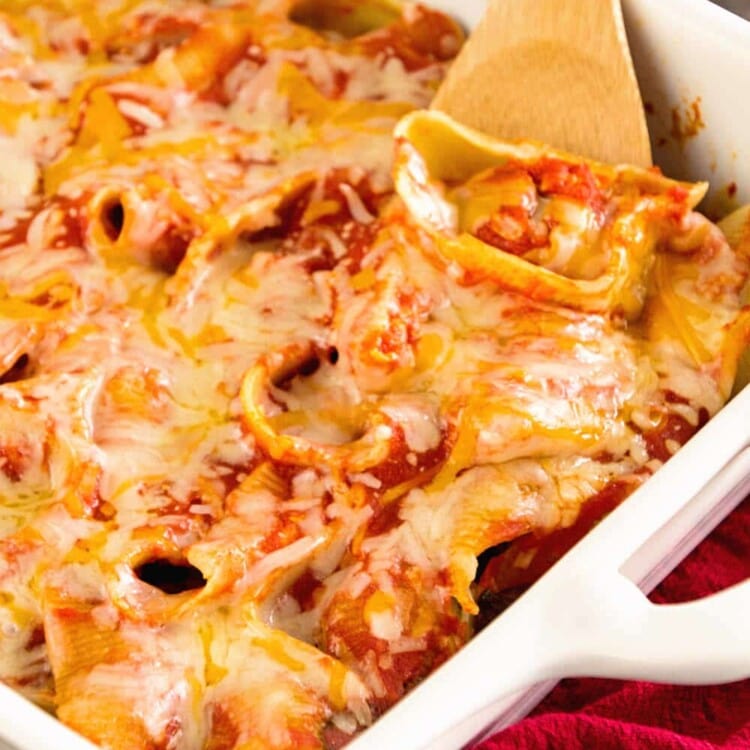 Easy meatball stuffed shells in a white baking dish with a wood spoon