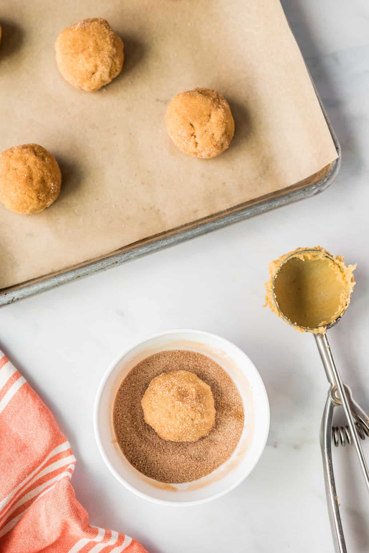 Rolling a ball of pumpkin snickerdoodle dough in cinnamon sugar