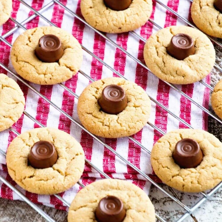 Overhead image of rolo peanut butter blossom cookies on a cooling rack over a red and white striped towel