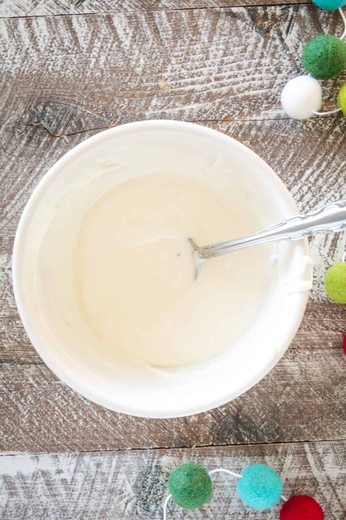 Cream colored bowl with melted white chocolate chips in it.