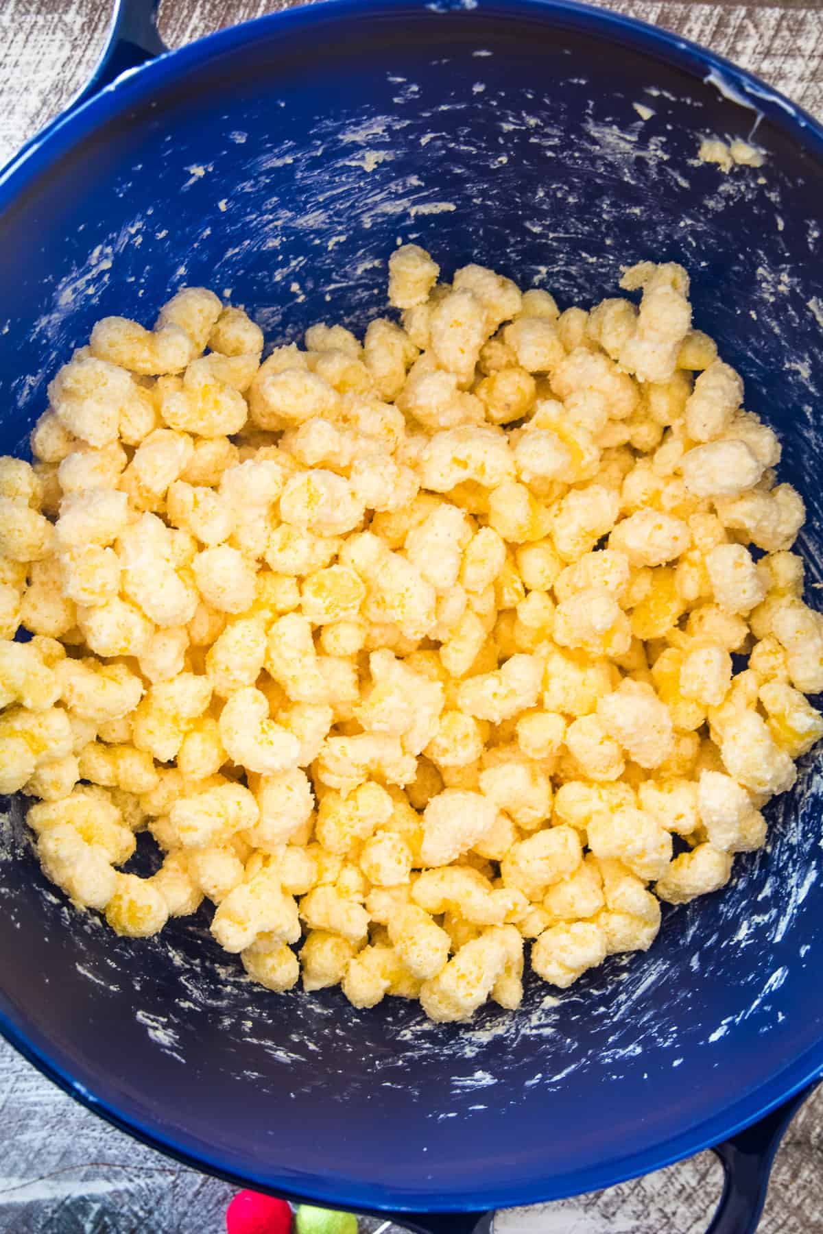 Blue bowl with puffcorn being mixed with white chocolate chips