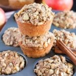 A six muffin tin of apple oat muffins with two more muffins stacked on top