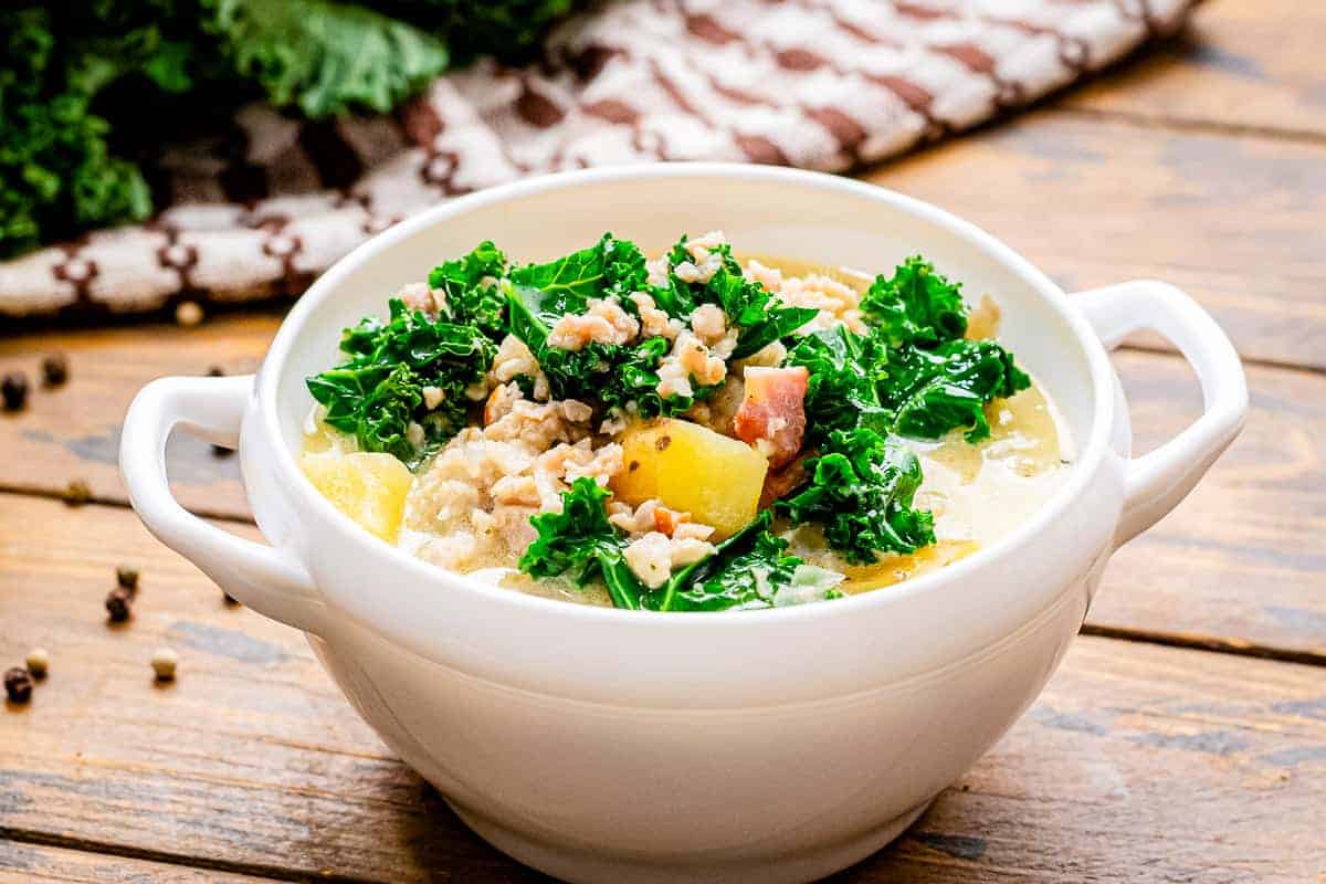 White bowl with slow cooker zuppa toscana in it
