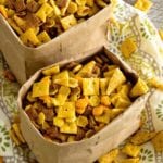 Two paper bags of ranch snack mix on a decorative table cloth