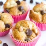 Four peanut butter and chocolate chip muffins in pink muffin liners on a white plate