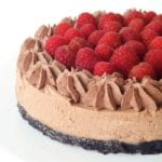 A raspberry chocolate cheesecake on a white cake stand