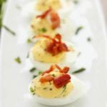Row of sour cream chive and bacon deviled eggs on a long white tray