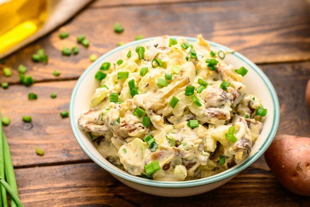 Bowl of homemade red potato salad on wood background