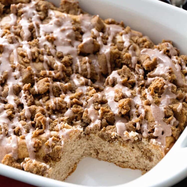 Cinnamon crumb coffee cake in a white baking dish with a piece missing from the corner
