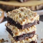 Three german chocolate brownies stacked on a whtie plate