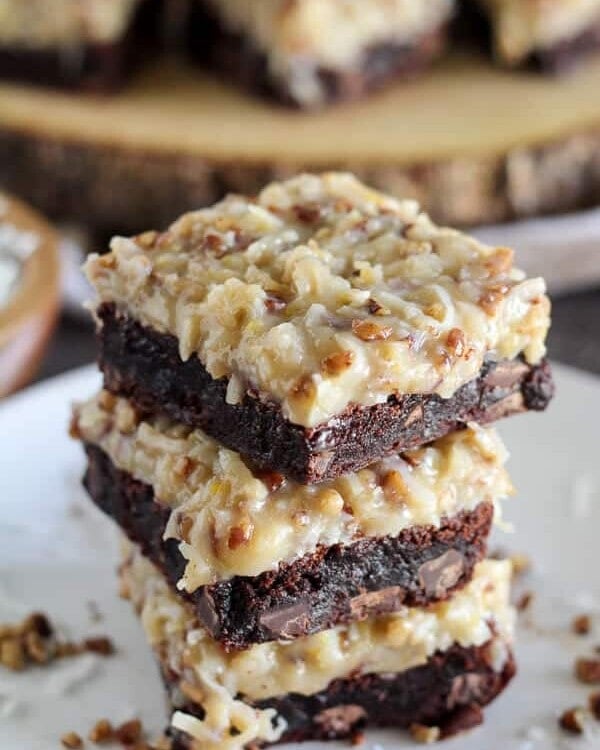 Three german chocolate brownies stacked on a whtie plate