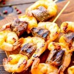 Grilled steak and shrimp kabobs on a cutting board