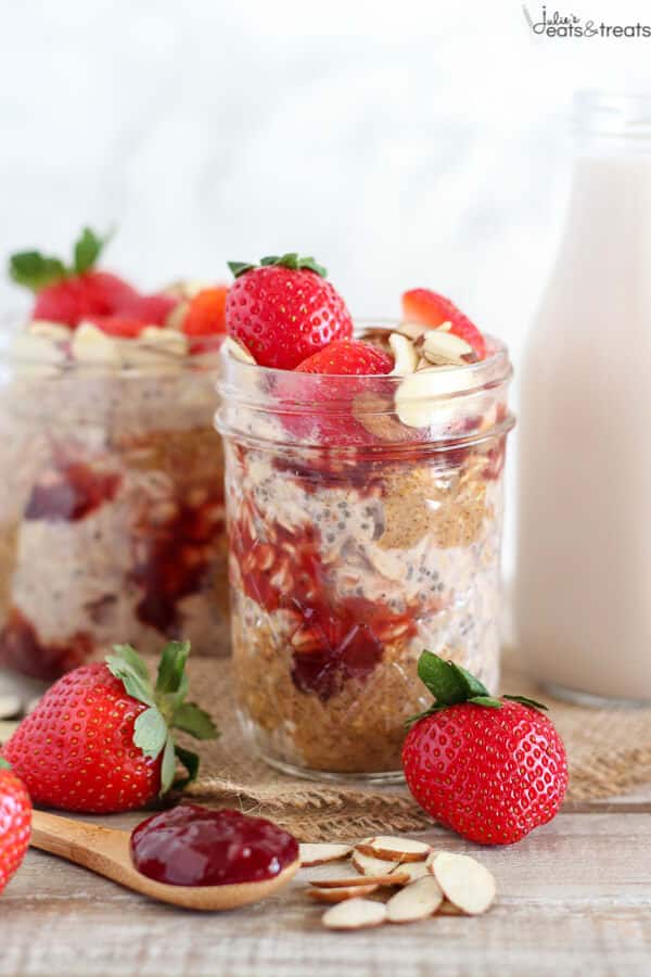 Glass jars filled with strawberry overnight oats and topped with slivered almonds and strawberries