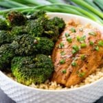 A white bowl of rice with broccoli and teriyaki salmon on top