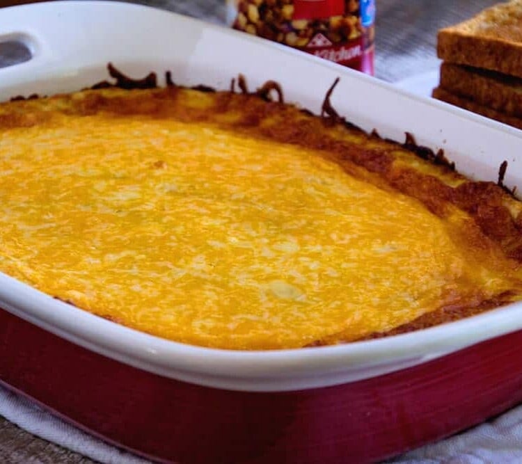 Overnight corned beef hash breakfast casserole in a white and red baking dish