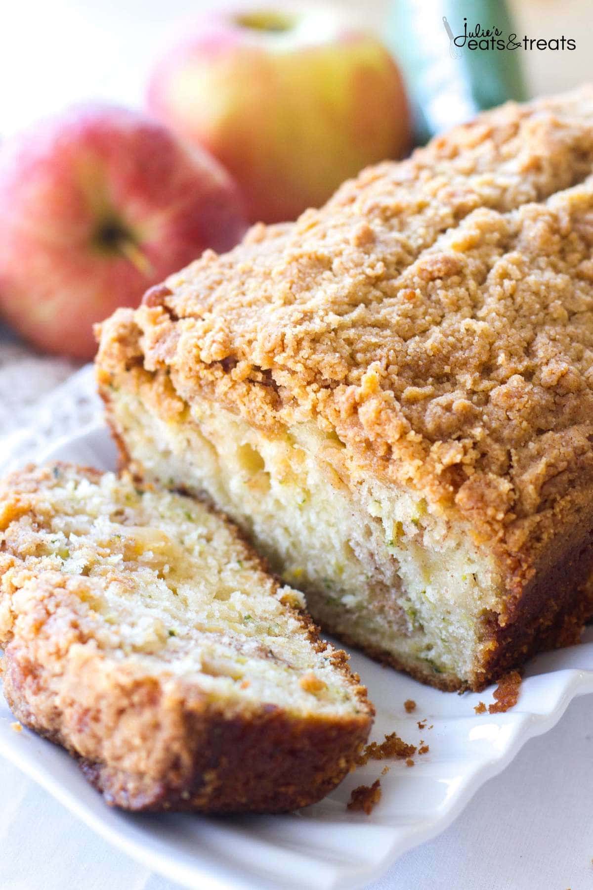 Zucchini Apple Bread sliced. The apple zucchini bread is surrounded by red apples and zucchini. 