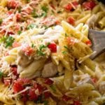 Wooden spoon scooping pasta out of a skillet full of one pot cajun chicken pasta