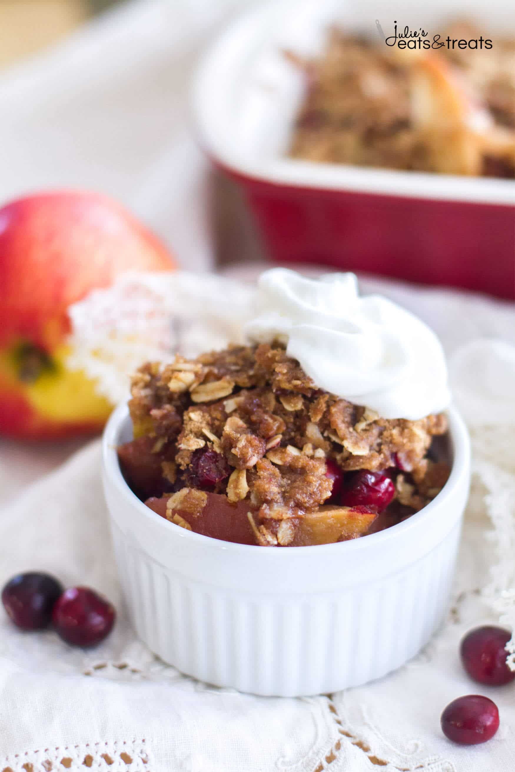 Cranberry Apple Cobbler in a white bowl topped with a dollop of whipped cream.