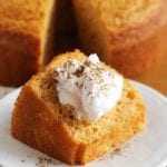 A slice of pumpkin angel food cake topped with whipped cream and ground cinnamon on a white plate