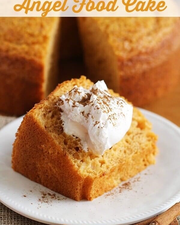 A slice of pumpkin angel food cake topped with whipped cream and ground cinnamon on a white plate